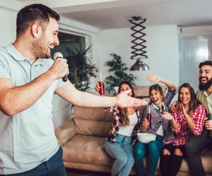 Group of friends playing karaoke at home