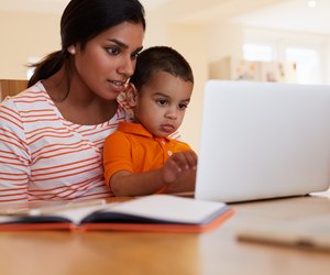 Mother And Son In Kitchen Looking At Laptop Together