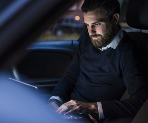 Businessman using laptop in car at night