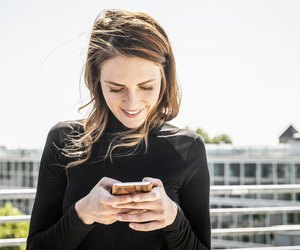 Smiling woman text messaging on roof terrace