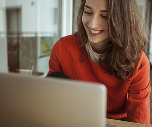 Smiling young woman using laptop on balcony