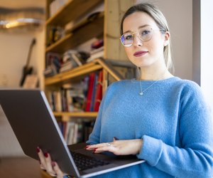 Female higher education student sitting on university stairway using laptop, portrait