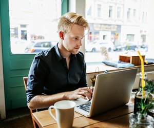 Young Man Working On Laptop In Cafe