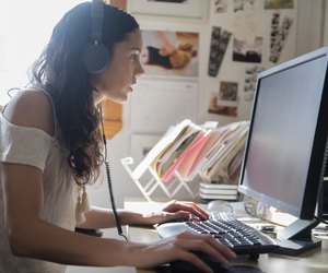 Hispanic woman listening to computer with headphones