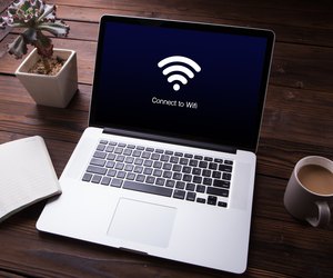 View of wi-fi connection on the laptop / computer screen with office equipment on wooden desk background