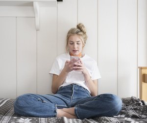Teen girl with phone sitting on bed