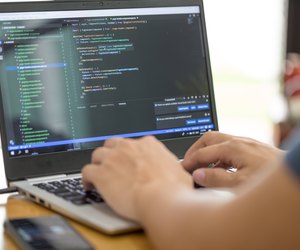 Freelance programmer or developer working at home and typing source code with laptop