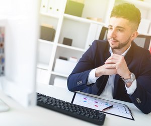 A young man sitting in the office at a computer Desk and working with documents.