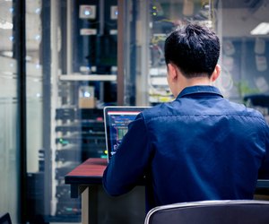 Technicians using laptop while analyzing server in server room