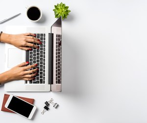 Female hands working on modern laptop. Office desktop on white background