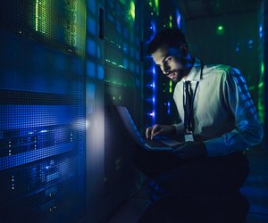 Handsome man is working in data centre with laptop.
