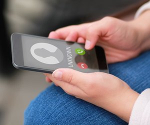 Close up of woman's hands with smartphone and unknown incoming phone call on it, fraud or scam schemes