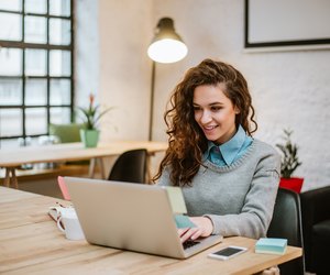 Successful young woman in modern office working on laptop.
