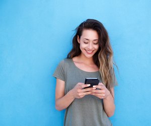 young smiling woman using mobile phone against blue background