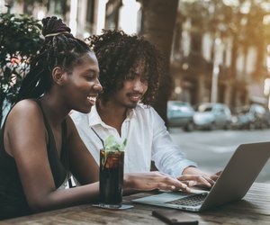 Interracial couple of friends in bar outdoors with the netbook