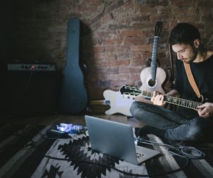 Young Musician Playing Guitar Sitting in front Notebook
