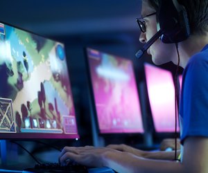 Team of Professional eSport Gamers Playing in Competitive MMORPG/ Strategy Video Game on a Cyber Games Tournament. They Talk to Each other into Microphones. Arena Looks Cool with Neon Lights.