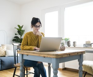 Woman sitting at table, using laptop