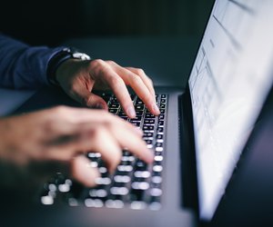 Close up of hands typing on laptop. Night work concept.
