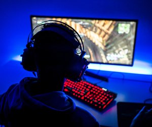 Rear View Of Boy Playing Video Game On Computer In Darkroom
