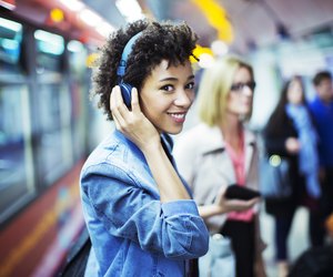 Smiling woman listening to headphones in subway