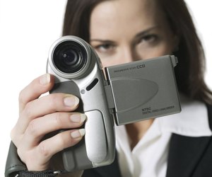 medium shot of a young adult woman as she take home movies with a video camera