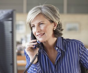 Mature businesswoman using telephone in office