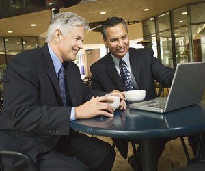 Businessmen in cafe using laptop