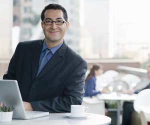 Smiling business man with computer in cafe.