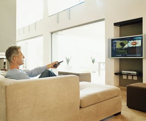 Mature Man Sits Watching TV in a Modern Home Interior