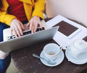 Woman hands with laptop tablet and tea outdoors in cafe
