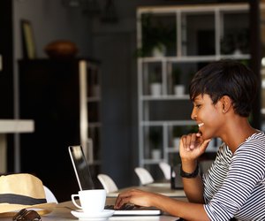Smiling young african american woman working on laptop