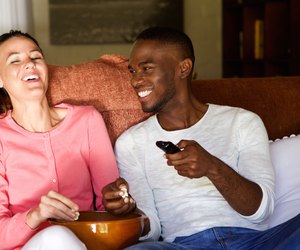 Happy young couple enjoying watching movie at home
