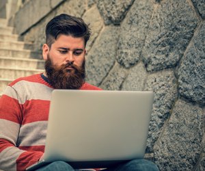 Young hipster sitting and using laptop