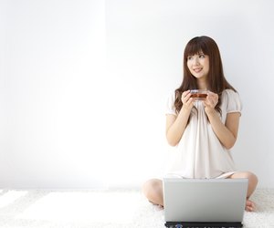 Young woman holding cup of tea, looking away, white background, copy space