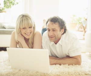 Man and woman using laptop on rug