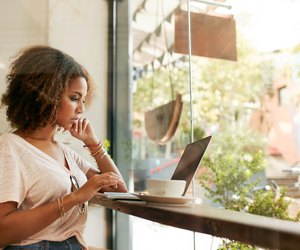 Young black woman at cafe using laptop