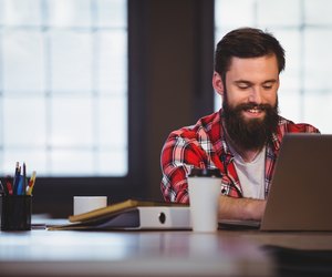 Hipster smiling while working on laptop