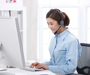 Young business lady wearing headset in front of laptop