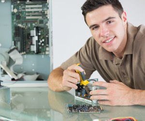 Handsome smiling computer engineer repairing hardware with pliers