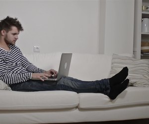 Young man working on laptop sitting on the couch