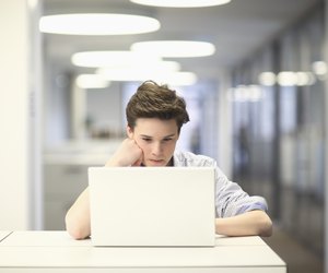 Teenage boy using laptop in office