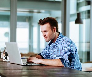 Young man at cafe typing on laptop