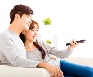 happy young couple watching tv in living room