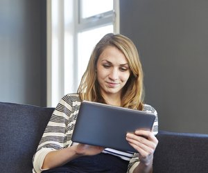 Girl using digital tablet on sofa