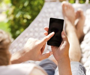 Man using mobile smart phone while relaxing in a hammock