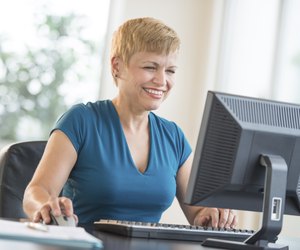 Happy Businesswoman Using Computer At Desk