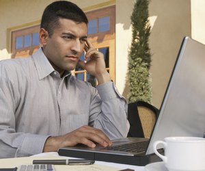 Mid adult man working on laptop at outdoor cafe table
