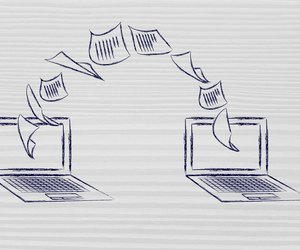laptops with documents flying from one screen to the other