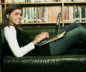 Student sitting on a couch with a laptop and listening to music